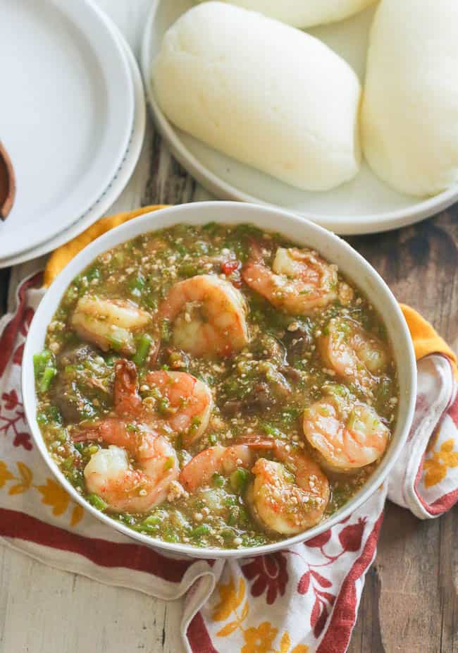 Okro soup in a white bowl with fufu in the background.