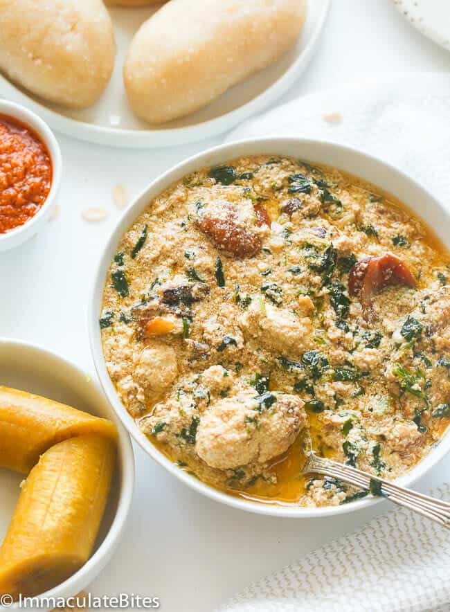 Egusi soup with lumps with fufu in the background.