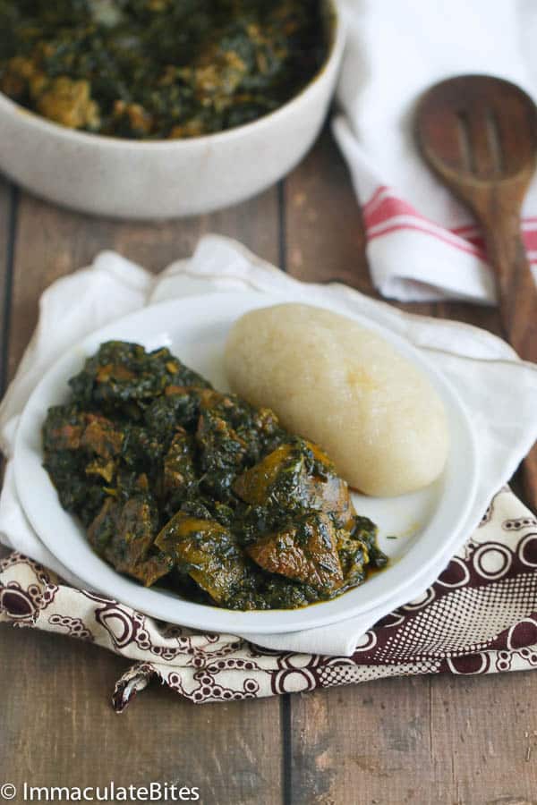 a serving of Eru Soup(Spinach/Okazi leaves) with fufu on a white plate
