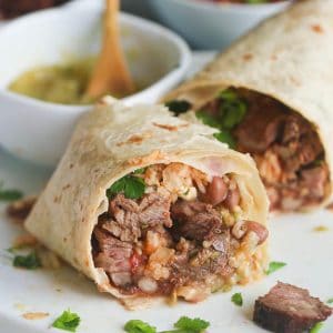 Steak Burrito sliced open for an inside view and salsa verde in the background