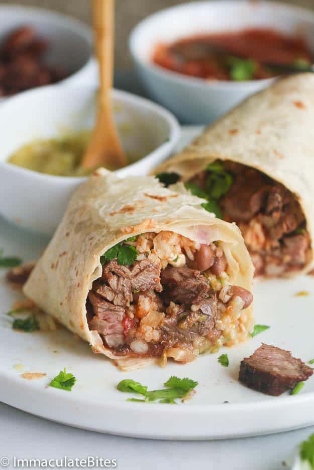 Steak Burrito sliced open for an inside view and salsa verde in the background