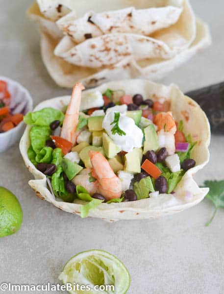 Squeezing lime over a shrimp salad nestled in a homemade tortilla bowl