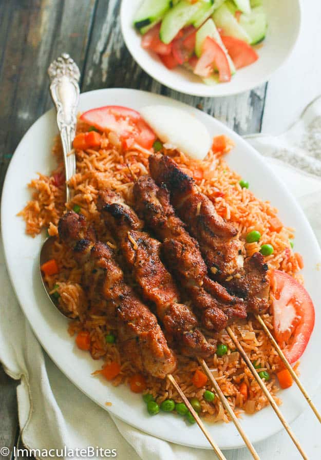 Oven Baked Jollof Rice served with Suya Skewers and tomato cucumber salad on the side.