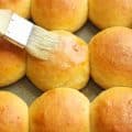 Brushing hot from the oven Hawaiian sweet rolls with melted butter