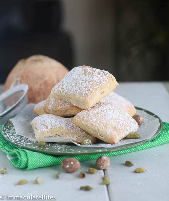 Diving into a plateful of soft baked mandazi dusted with powdered sugar for an insanely delicious treat