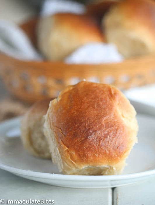 Hawaiian Coconut bread rolls recipe on a white plate with a basket full in the background