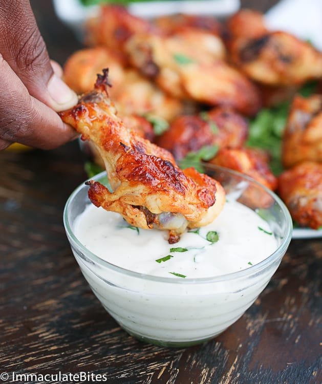 Dipping a spicy chicken wing into a delicious tzatziki sauce