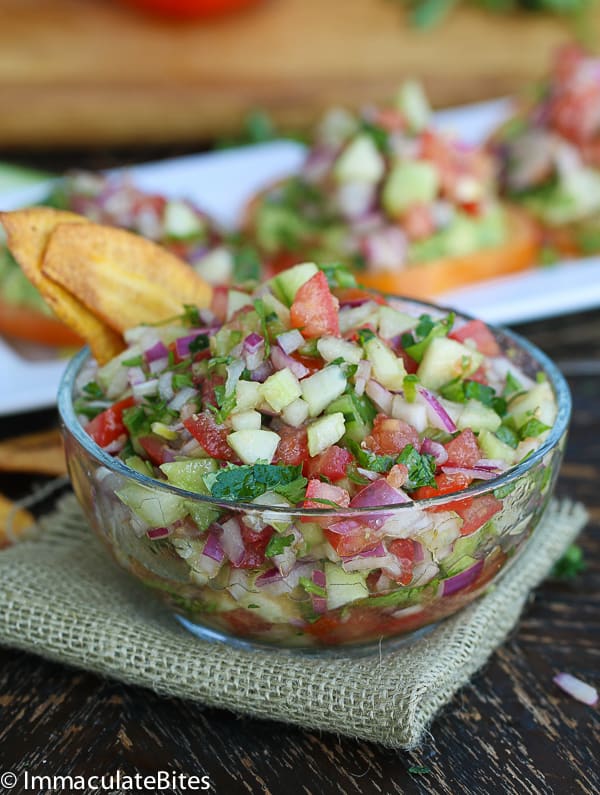 Kachumbari in a clear medium bowl served with dipped plantain chips