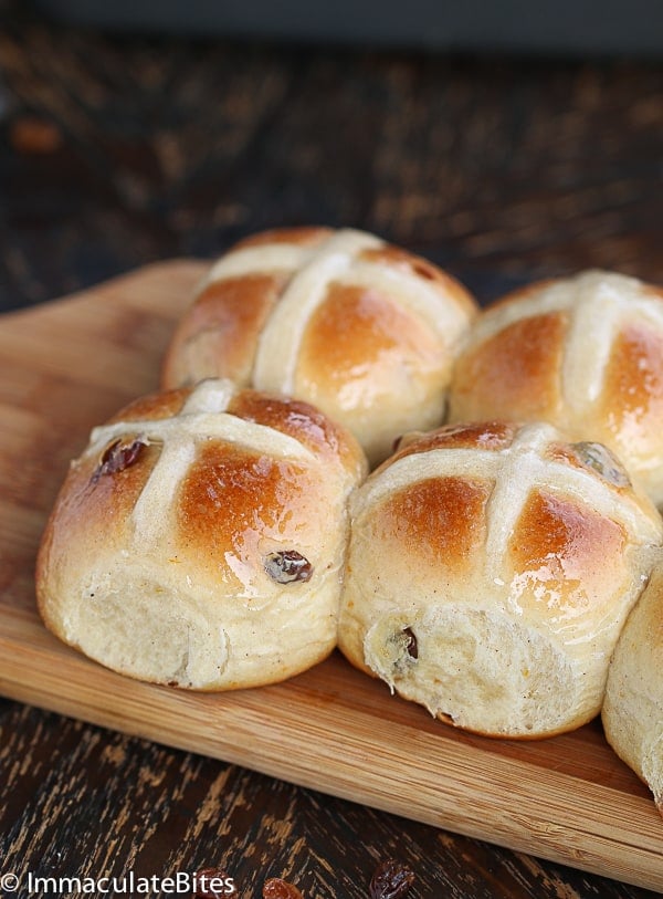 Glossy Hot Cross Buns with Raisins on a Chopping Board