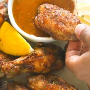Dipping baked jerk chicken wings in a delectable hot sauce
