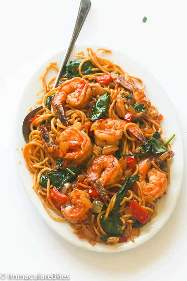 a white platter of spicy shrimp tomato spinach pasta