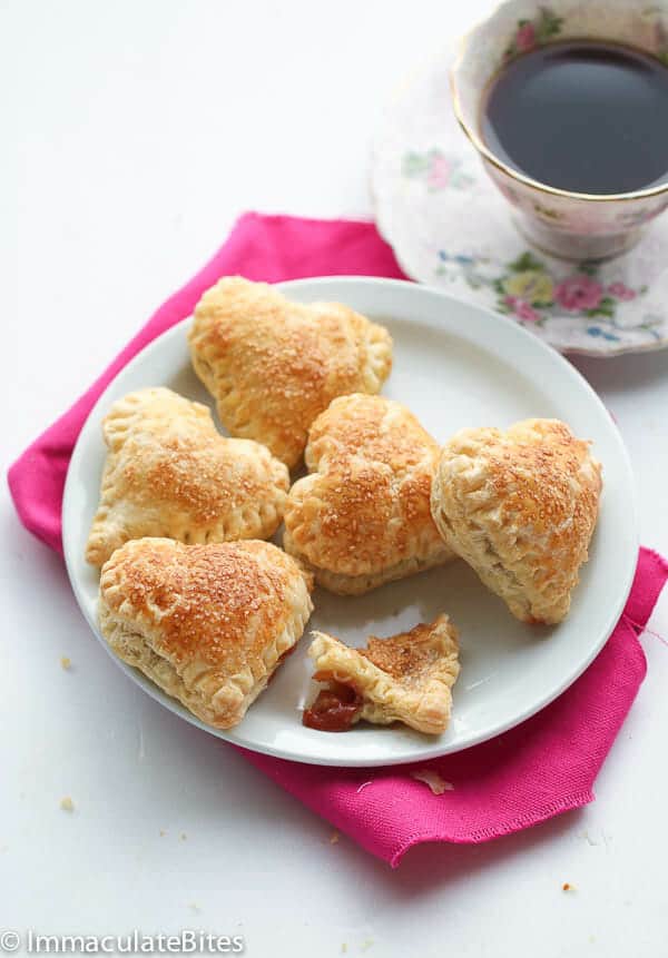 Five pastries on a plate with a cup of coffee next to the plate. 