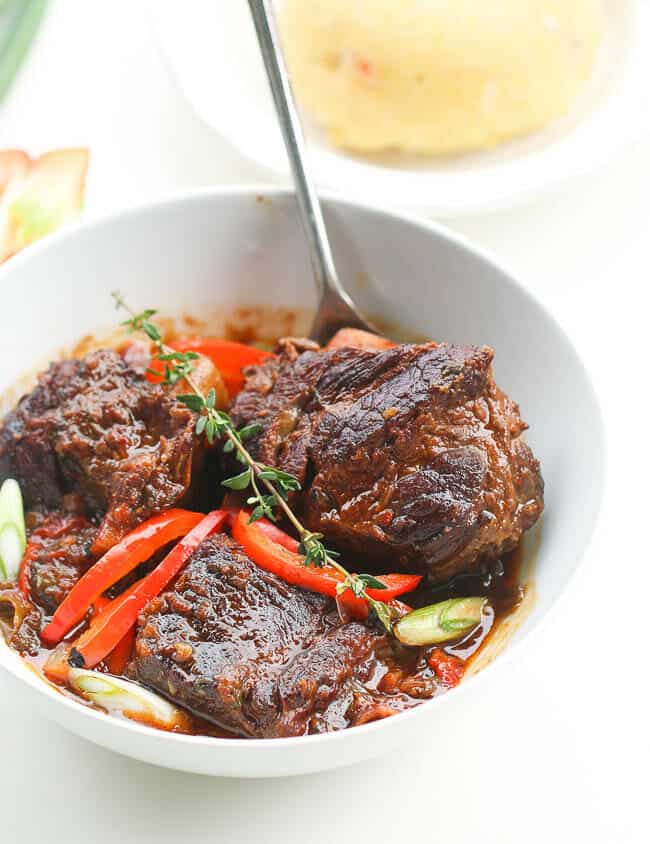 Extremely fork-tender beef short ribs stew in a white bowl