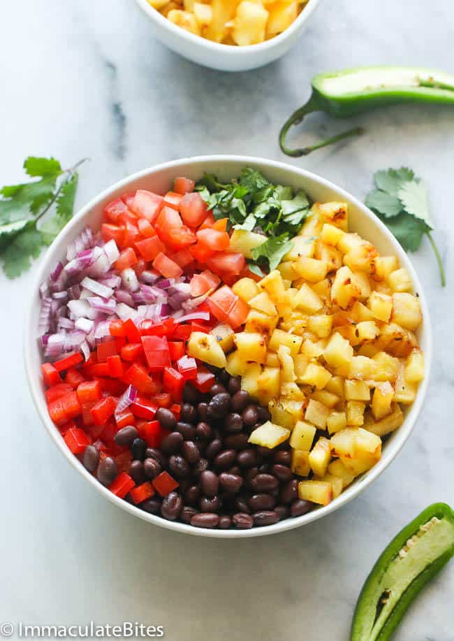 a big white bowl of grill pineapple black bean salsa ingredients