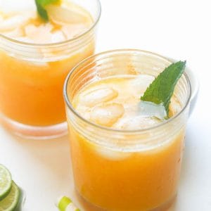 Two refreshing glasses of mango lemonade with mint leaves