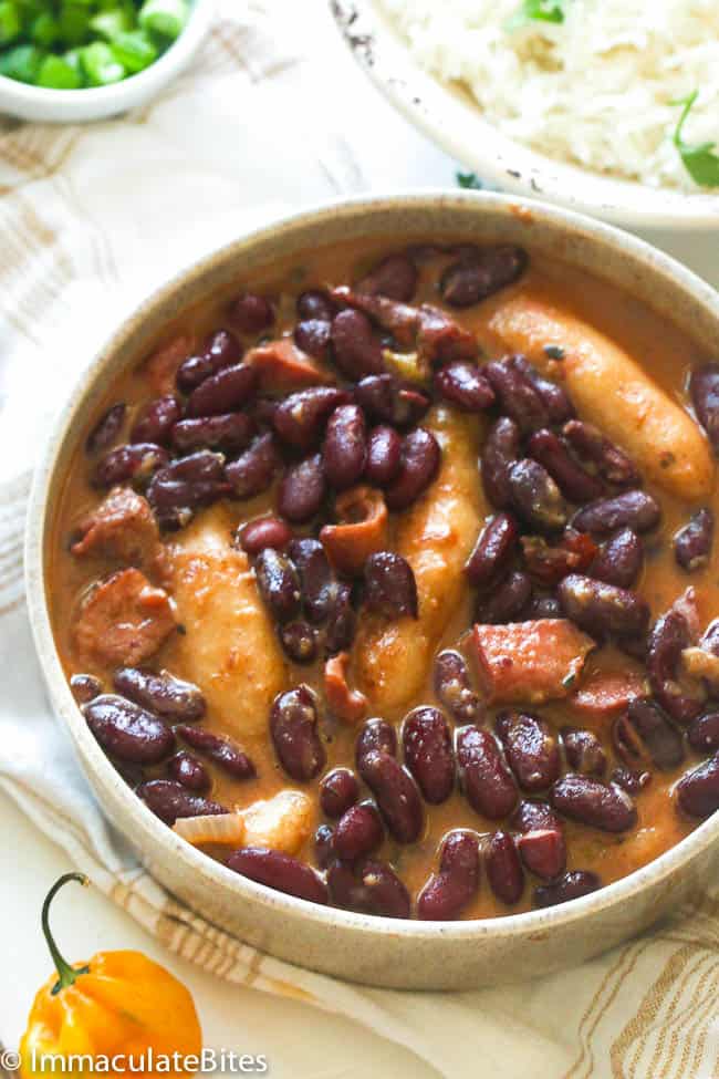 Serving up a bowl of Caribbean stewed kidney beans with coconut rice in the background