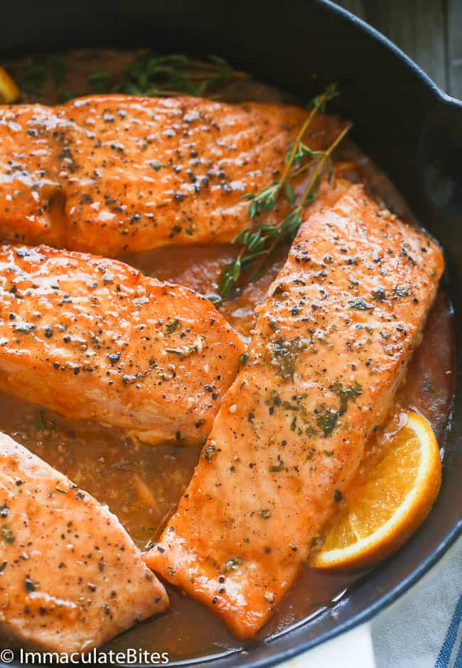 A Pan of Orange Honey Glazed Salmon Fillets Garnished with Rosemary Sprigs and Lemon Slices