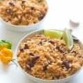 Two bowls of Caribbean rice and beans with lime wedges