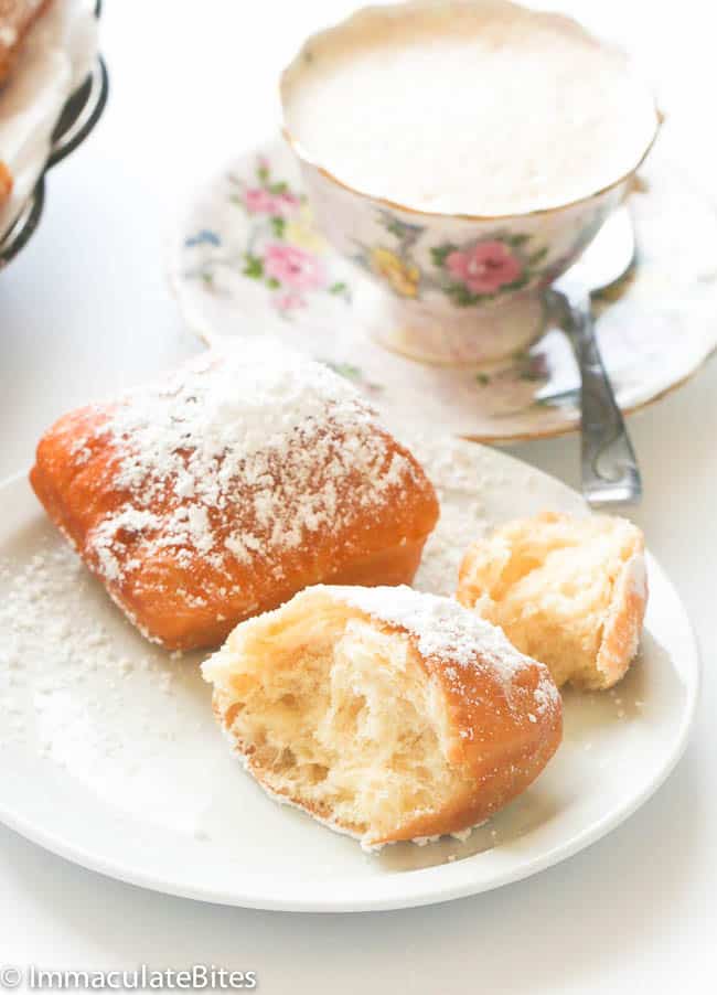 Half-opened Beignet on a plate with coffee in the background