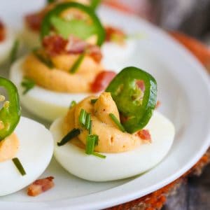 deviled eggs with bacon jalapenos on a white plate