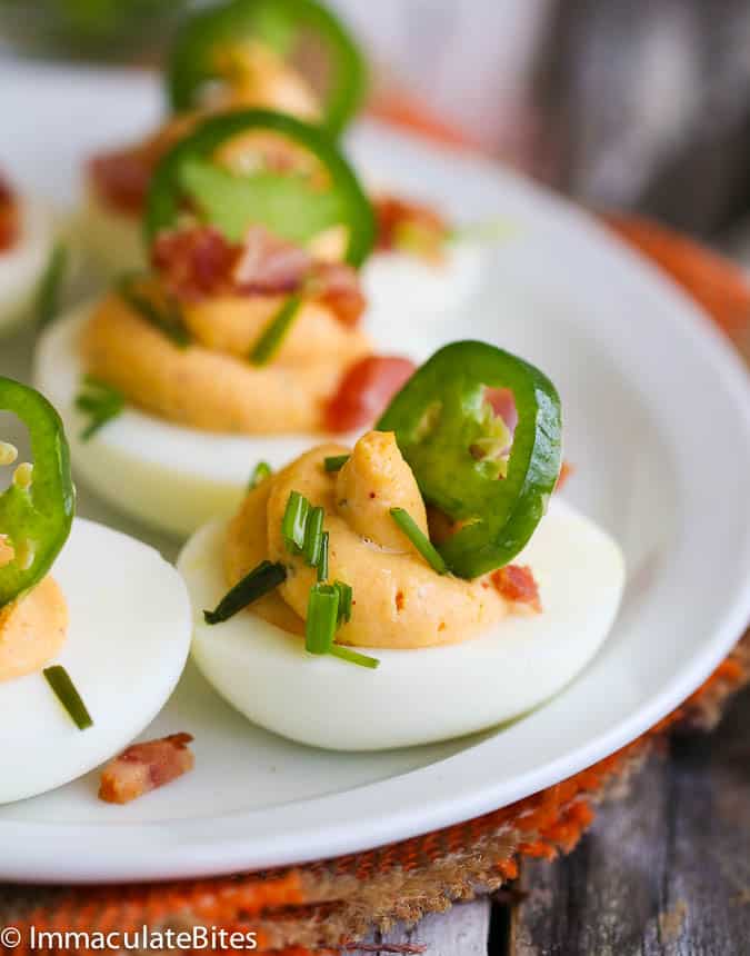 deviled eggs with bacon jalapenos on a white plate