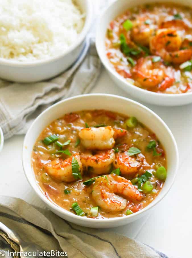 Two bowls of Shrimp Étouffée  with rice in the background.