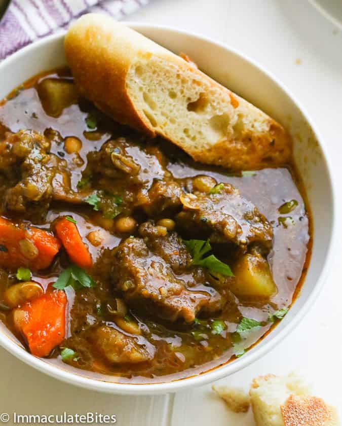 A Bowl of Oxtail Soup Served with a Slice of Crusty Bread