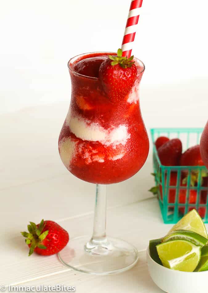 Strawberry daiquiri in a fancy glass with a red and white straw