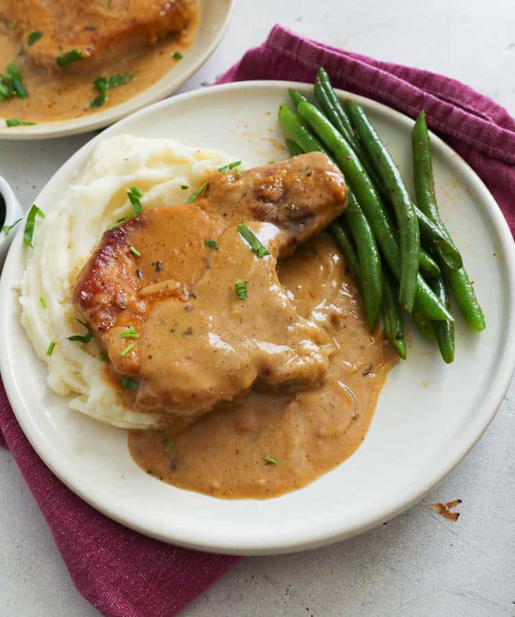 Smothered Pork Chops in a Plate with Mashed Potatoes and Green Beans
