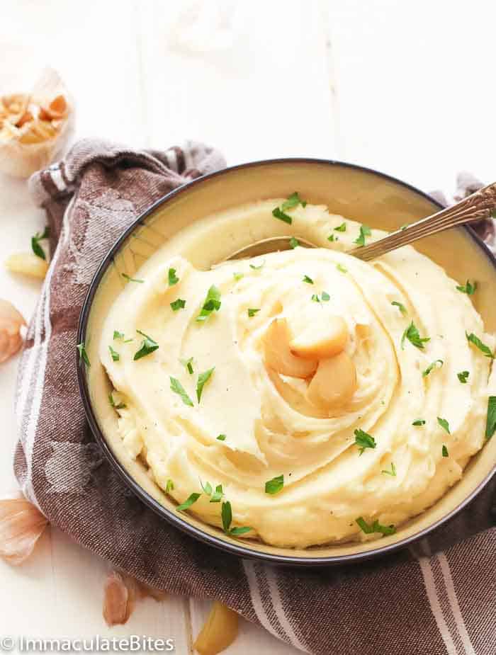 A Plateful of Garlic Mashed Potatoes Garnished with Garlic Cloves and Parsley