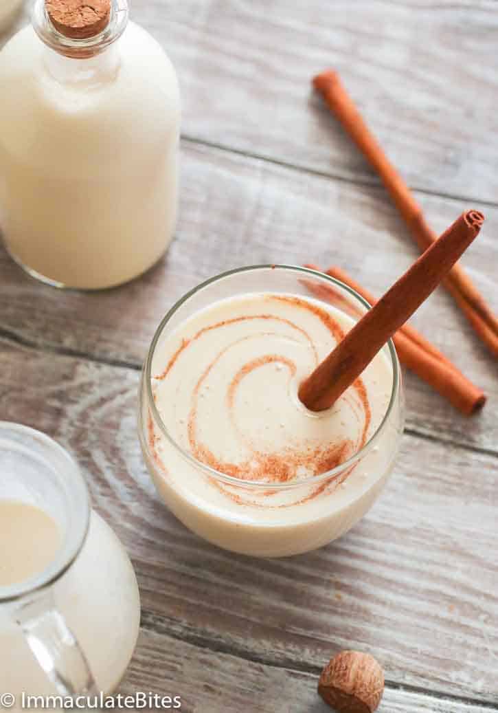 Coquito in a fancy glass garnished with a cinnamon stick