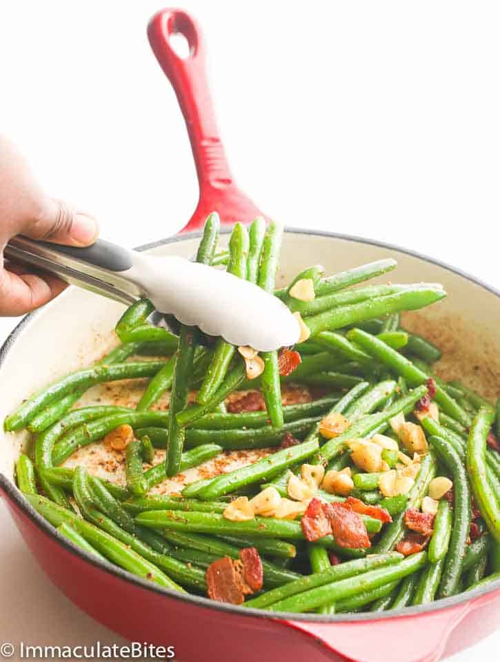 Green Beans with Bacon in a red skillet being served with tongs