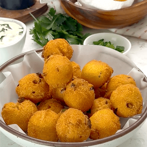 Serving up a bowl full of freshly fried hush puppies.