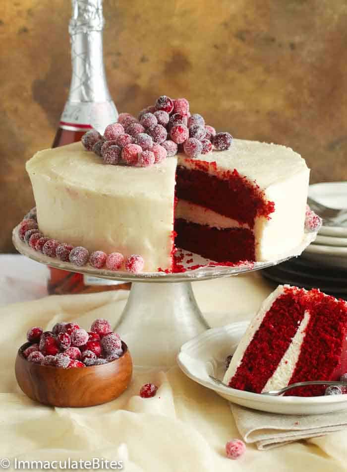 sliced red velvet cake with wine in the background and a cupful of candied raspberries
