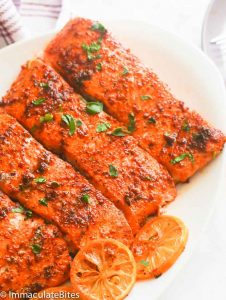 Ridiculously tasty Oven Baked Salmon with lemon slices on a white platter.