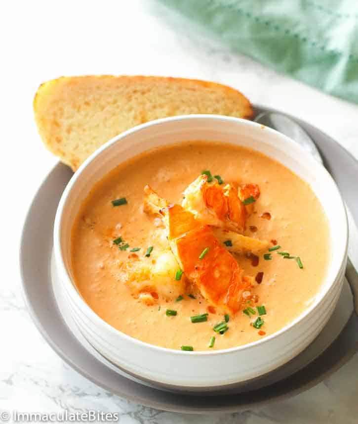 A decadent bowl of lobster bisque with a slice of garlic bread