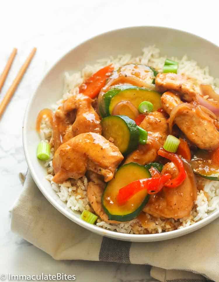 A Bowl of Stir Fry Chicken and Vegetables Served over White Rice