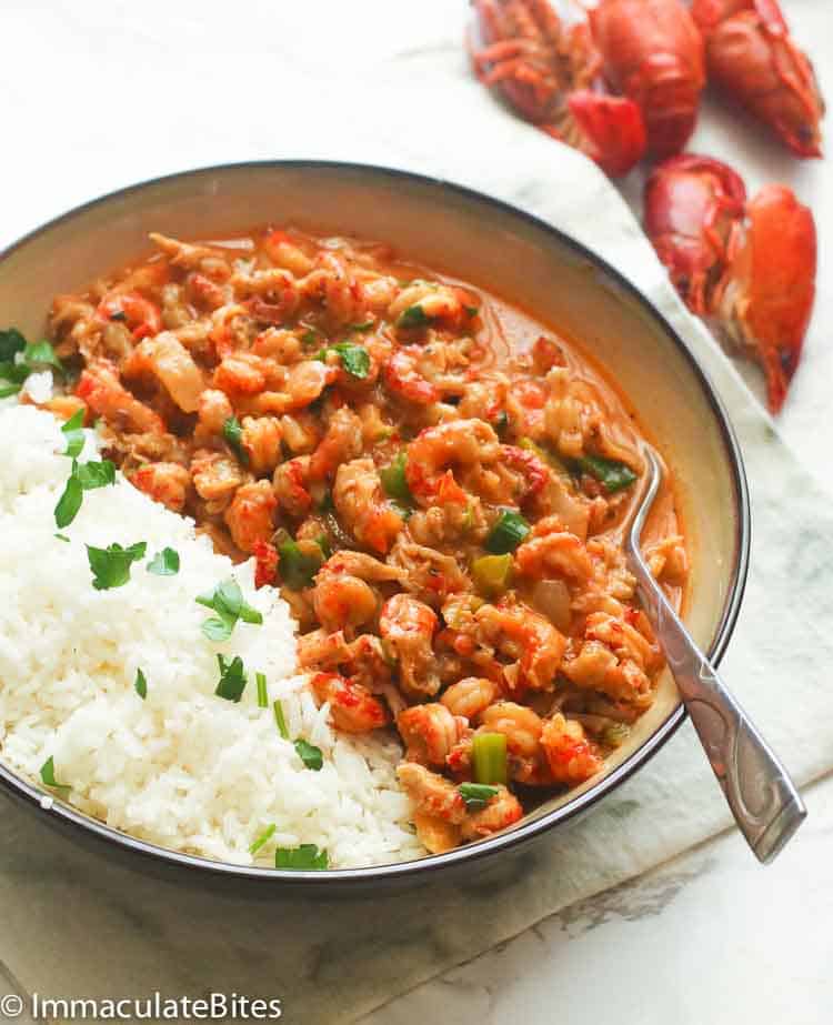 plated crawfish etouffee served with rice and some crawfish pieces in the background