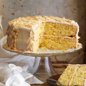 Coconut Cake on a tall cake plate and a slice on a brown dessert plate