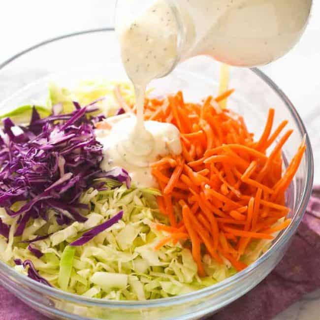 Drizzling creamy coleslaw dressing over a freshly made salad for the perfect cookout side