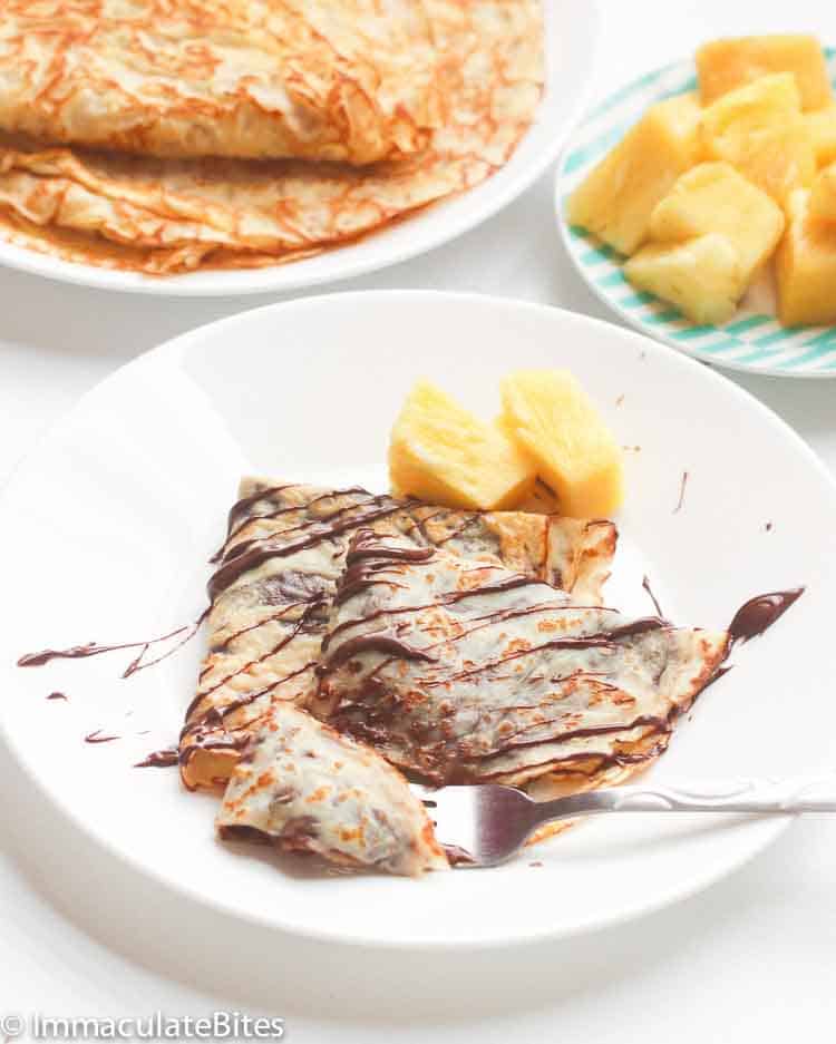 Easy crepes filled with chocolate, drizzled with more chocolate sauce, and served with fresh pineapple