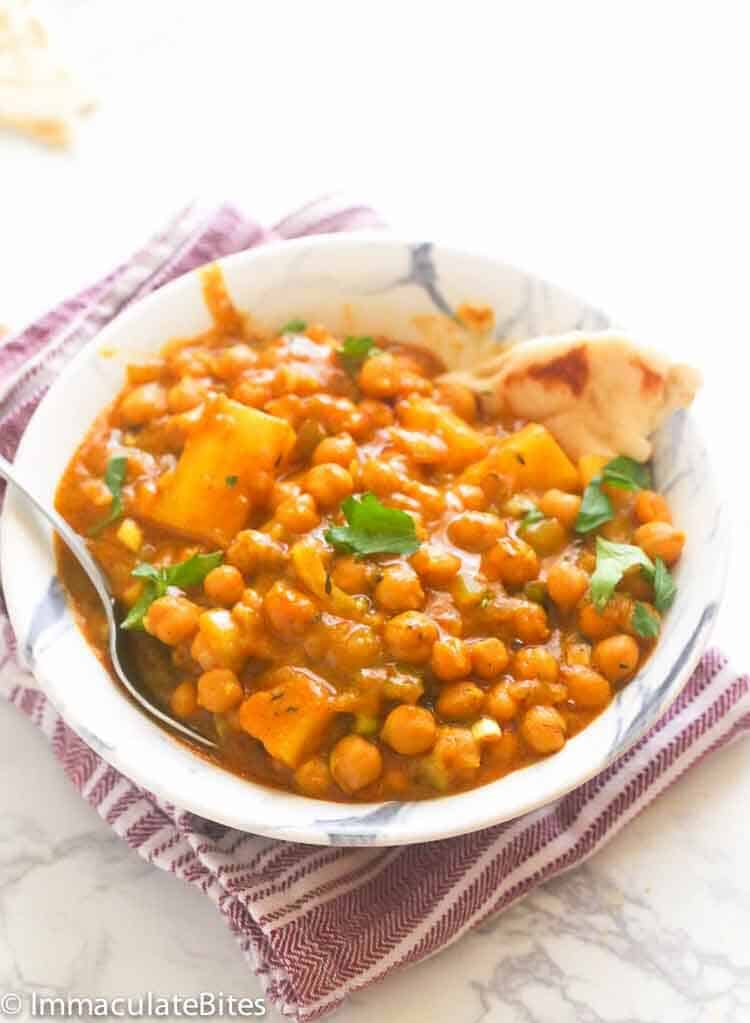 Chickpea curry with coconut milk and garnished with parsley in a white bowl
