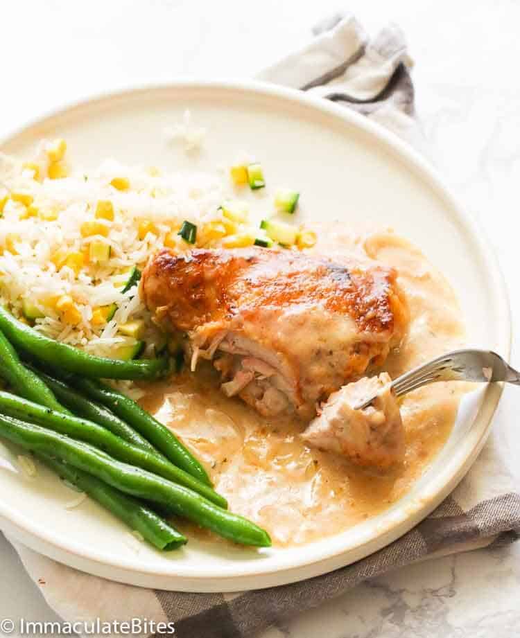 A forkful of creamy smothered chicken with green beans and rice with veggies. 