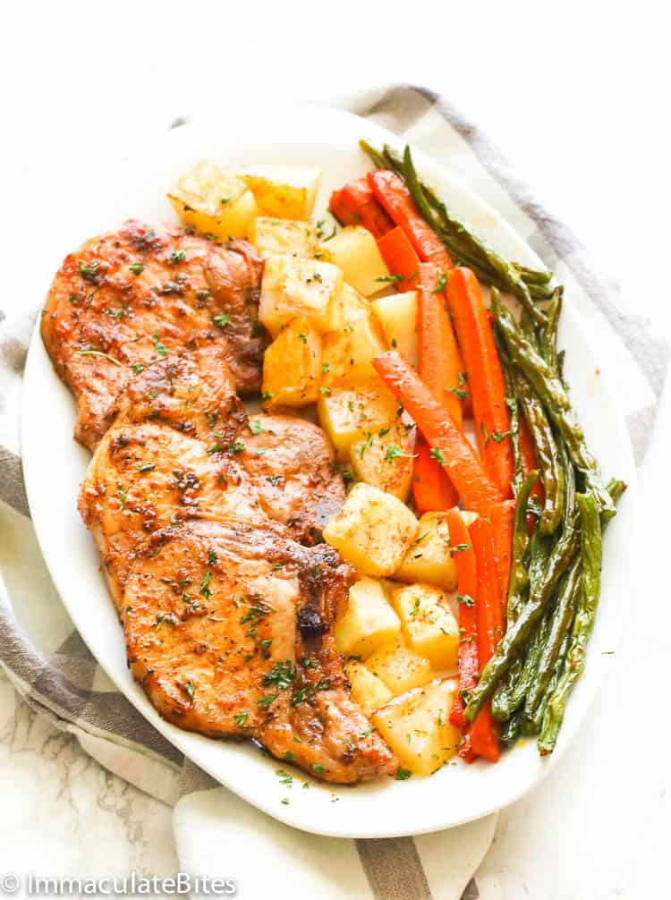 Delicious oven-roasted pork chops and roasted vegetables on a white platter