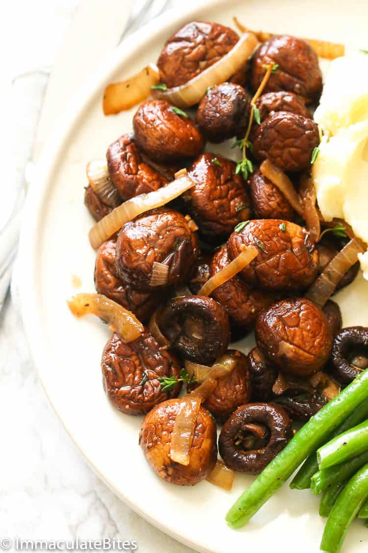 a plate of sauteed mushrooms served with mashed potatoes and green beans