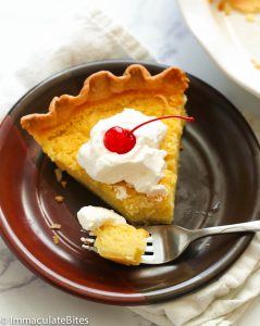 Enjoying a bite of sweet and tart Buttermilk Pie topped with whipped cream and a cherry