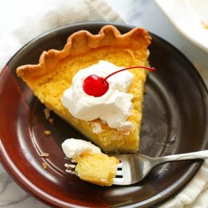 Enjoying a bite of sweet and tart Buttermilk Pie topped with whipped cream and a cherry