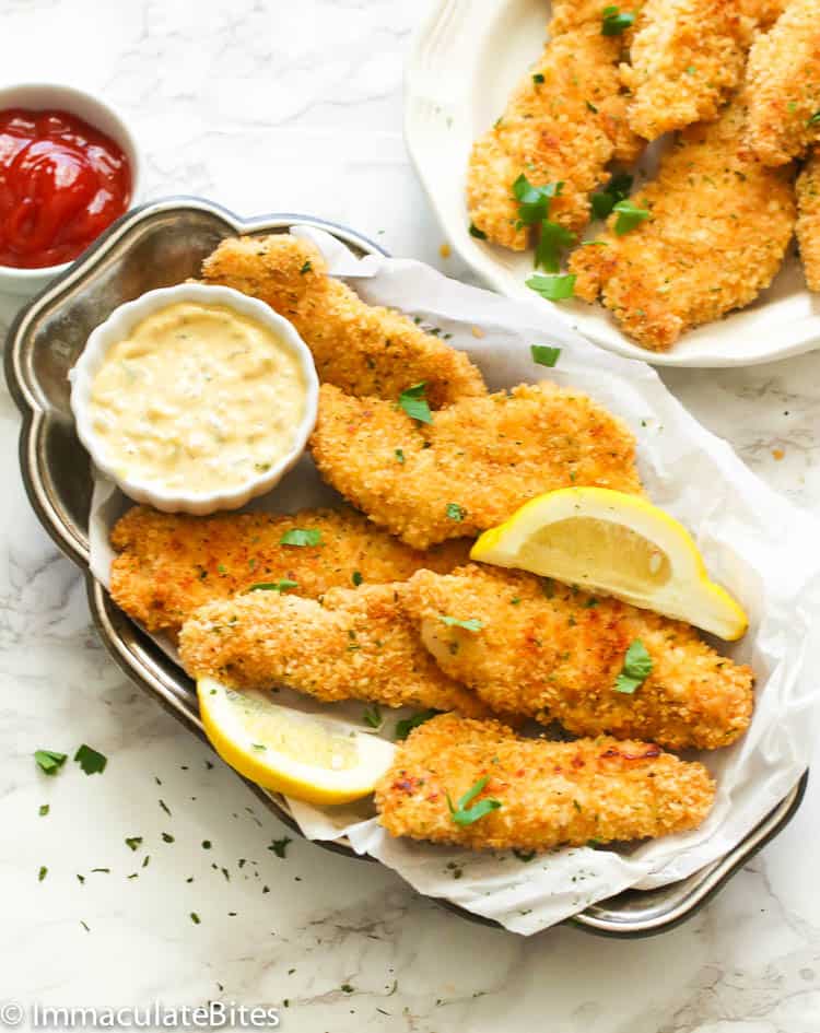 Insanely good baked chicken tenders with a variety of dipping sauces and lemon wedges ready for the Super Bowl