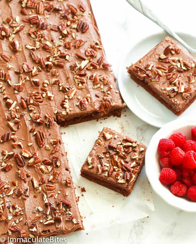 Texas Sheet Cake with slices removed and raspberries on the side