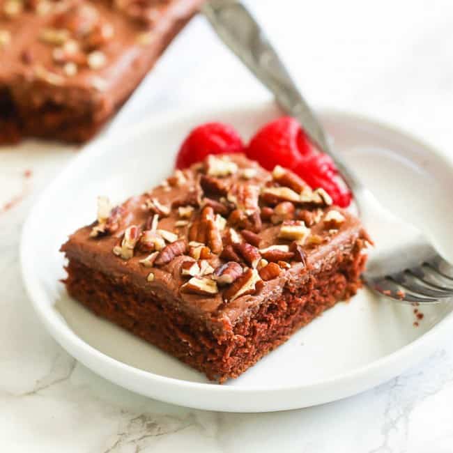 A serving of chocolate sheet cake with fresh raspberries on the side.